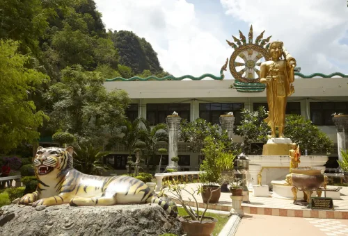 Golden Buddha and tiger statues in the garden of Tiger Cave Temple, Krabi.