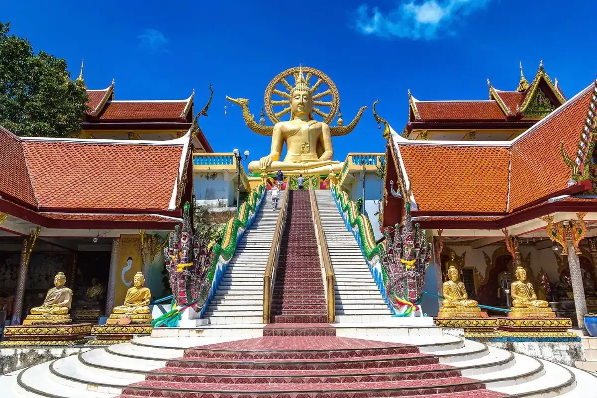 Golden Big Buddha statue and temple architecture under blue sky in Koh Samui, Thailand.