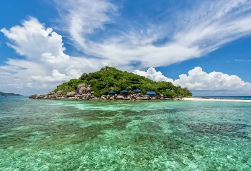 Green tropical island surrounded by coral reefs and shallow turquoise water near Koh Tao.