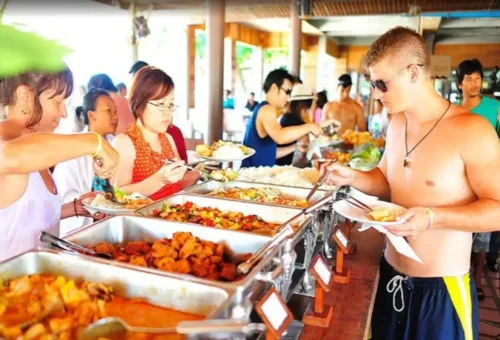 Tourists enjoying a buffet lunch with Thai dishes at a beachfront restaurant on Koh Tao