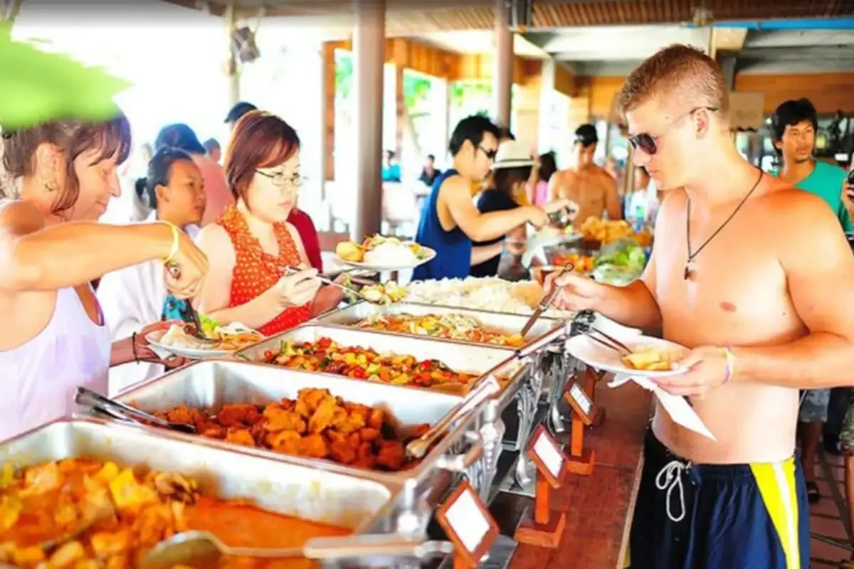 Tourists enjoying a buffet lunch with Thai dishes at a beachfront restaurant on Koh Tao