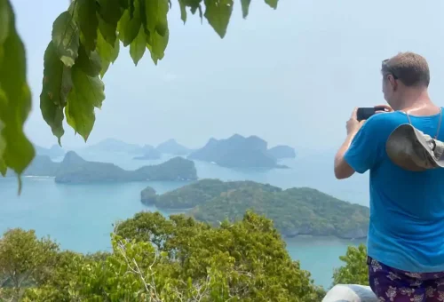 Traveler taking photos from a viewpoint overlooking islands and blue sea at Angthong National Marine Park.