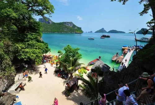 Tourists arriving by speedboat at Angthong Marine Park’s white sand beach surrounded by emerald water and islands.
