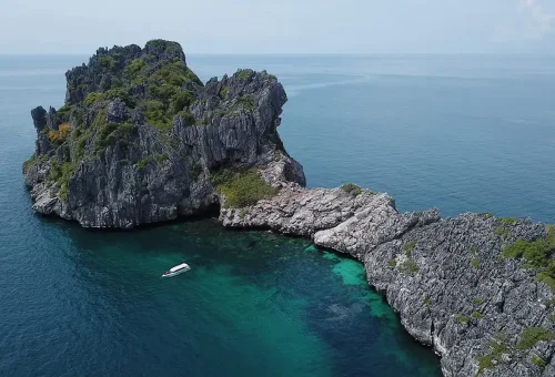 Aerial view of limestone cliffs and clear turquoise sea at Angthong National Marine Park in the Gulf of Thailand.