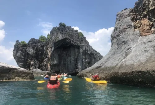 Travelers kayaking at Koh Sam Sao, exploring limestone cliffs and sea caves in Angthong Marine Park, Thailand.