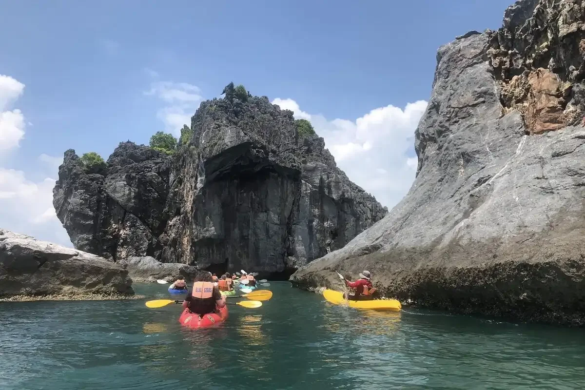 Travelers kayaking at Koh Sam Sao, exploring limestone cliffs and sea caves in Angthong Marine Park, Thailand.