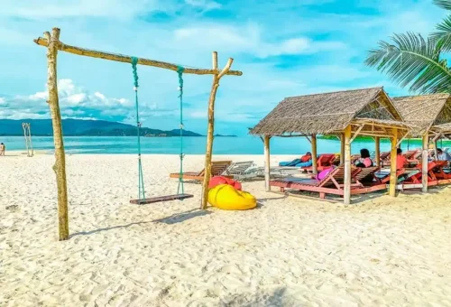Wooden beach huts, swings, and sunbeds on Coral Island (Samui), a perfect tropical escape offered by Phuket Travel Store.