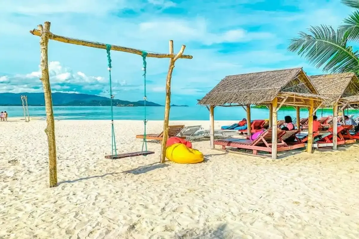 Wooden beach huts, swings, and sunbeds on Coral Island (Samui), a perfect tropical escape offered by Phuket Travel Store.