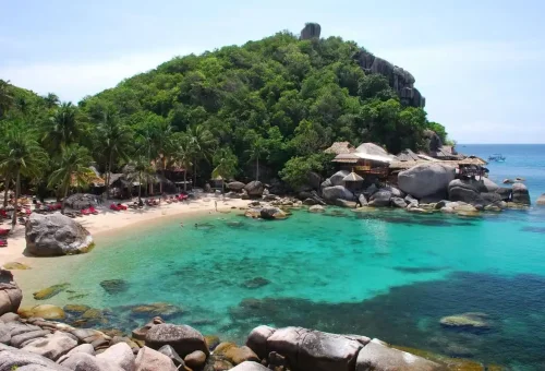 Hidden beach with crystal-clear water and palm trees on Koh Phangan