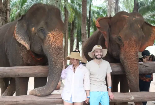 Couple smiling with gentle elephants during the ethical Krabi Elephant Shelter tour by Phuket Travel Store.