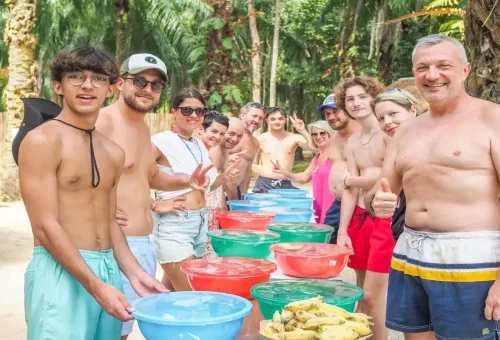 Tourists smiling while preparing elephant meals as part of the Cook and Feed experience at Krabi Elephant Shelter.