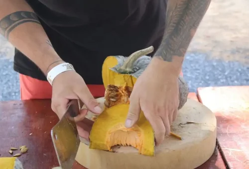 Close-up of hands slicing pumpkin for elephant food at Krabi Elephant Shelter with Phuket Travel Store.