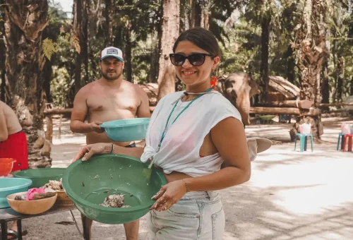 Smiling woman holding a bowl of elephant food during the Get Up Close program at Krabi Elephant Shelter.