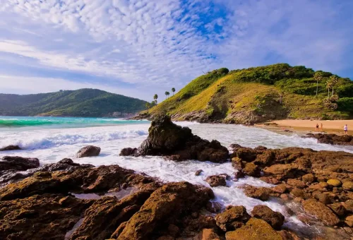 Private Phuket City Tour – rocky coastline at Yanui Beach with emerald waves and lush hills in Phuket with Phuket Travel Store.