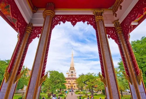 Private Phuket City Tour – Wat Chalong viewed through ornate red temple arch, showcasing Phuket’s cultural heritage with Phuket Travel Store.