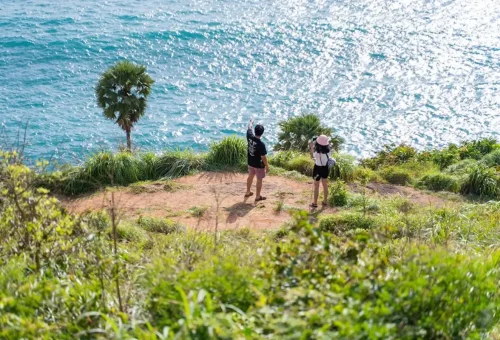 Tourists enjoying the Promthep Cape hillside viewpoint overlooking the sea.