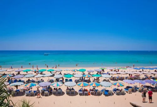 Colorful beach umbrellas and turquoise waters at Karon Beach Phuket.