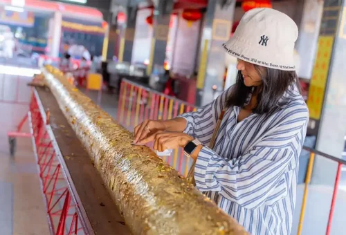 Tourist placing gold leaf for good luck at a local Phuket Chinese shrine.