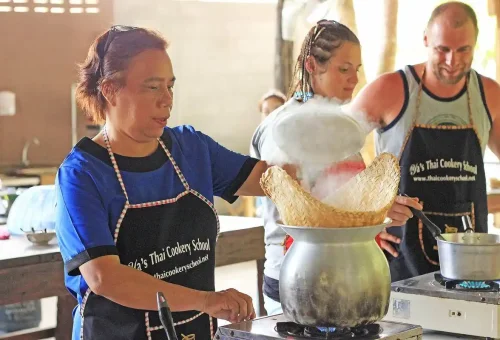 Thai chef steaming traditional sticky rice during a hands-on cooking lesson in Krabi.