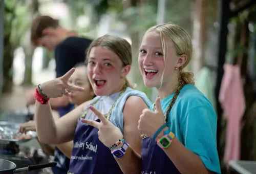 Two teenage students posing happily during their Thai cooking class experience.