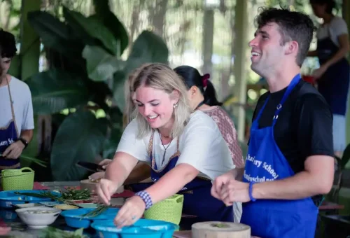 Guests enjoying a fun Thai cooking session, preparing herbs and fresh ingredients.