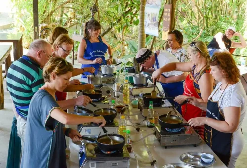 Participants practicing Thai cooking techniques during a hands-on class in Krabi.