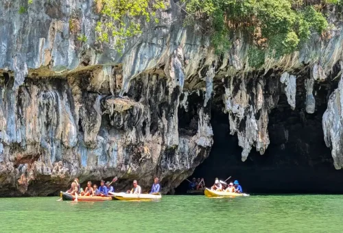 Travelers kayaking into a limestone cave in Phang Nga Bay on a James Bond private speedboat tour.
