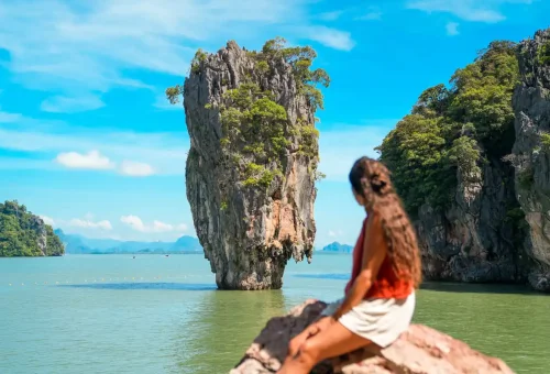 Woman looking at the iconic James Bond Island rock formation in Phang Nga Bay, Thailand.