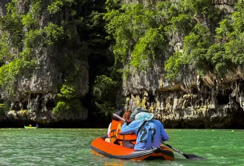 Kayaking through emerald green waters surrounded by limestone cliffs in Phang Nga Bay.