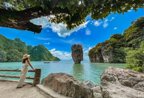 Woman enjoying the scenic view of James Bond Island from the wooden viewpoint deck in Phang Nga Bay.