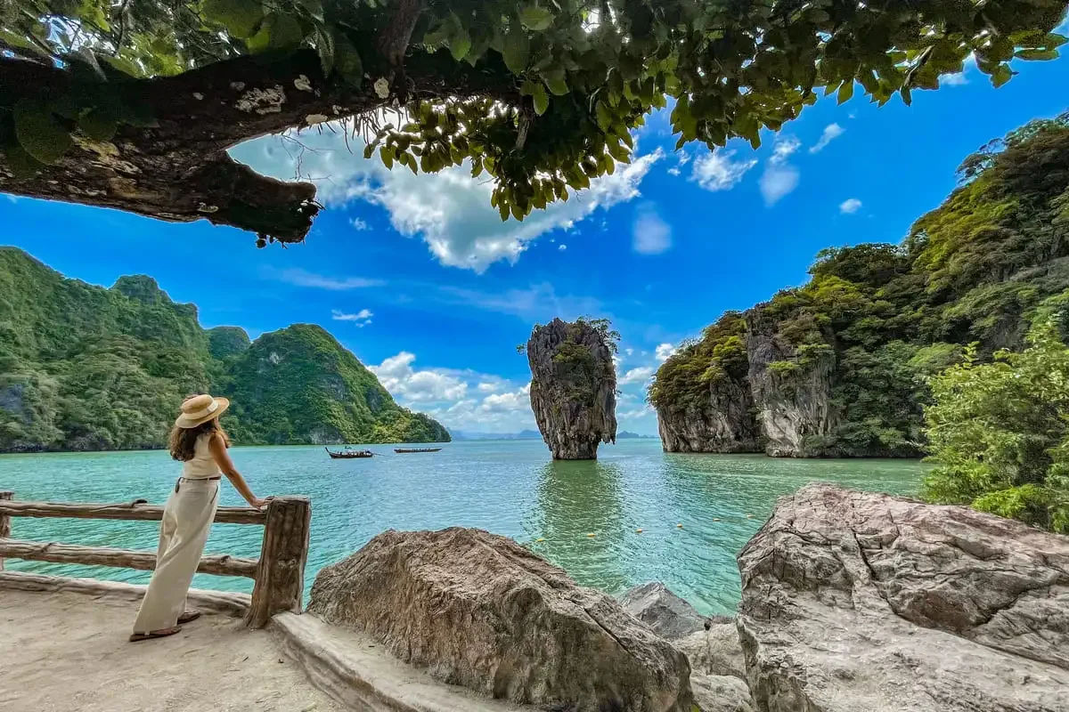 Woman enjoying the scenic view of James Bond Island from the wooden viewpoint deck in Phang Nga Bay.