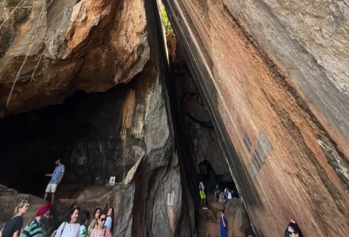 Tourists exploring a narrow cave passage and ancient rock formations in Phang Nga Bay on a private speedboat tour.
