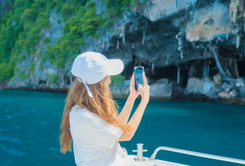 Woman taking photos of limestone cliffs and sea caves during a Phi Phi Islands private tour.Woman taking photos of limestone cliffs and sea caves during a Phi Phi Islands private tour.