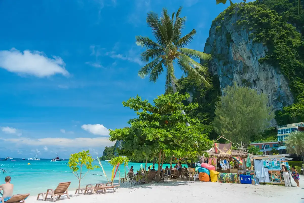 Beachfront bar with palm trees, drinks and sunbeds overlooking turquoise water at Phi Phi Don.