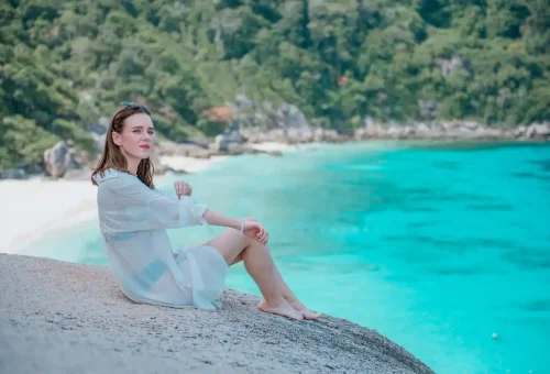 Woman sitting at scenic Similan Islands viewpoint above turquoise lagoon