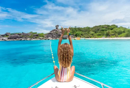 Traveler relaxing on the bow of a private speedboat with turquoise water at Similan Islands