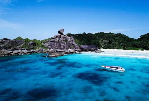 Private speedboat anchored at Similan Islands Donald Duck Bay with iconic Sail Rock