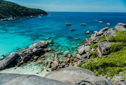 Crystal-clear turquoise bay with boats and rocky coastline at Similan Islands viewpoint
